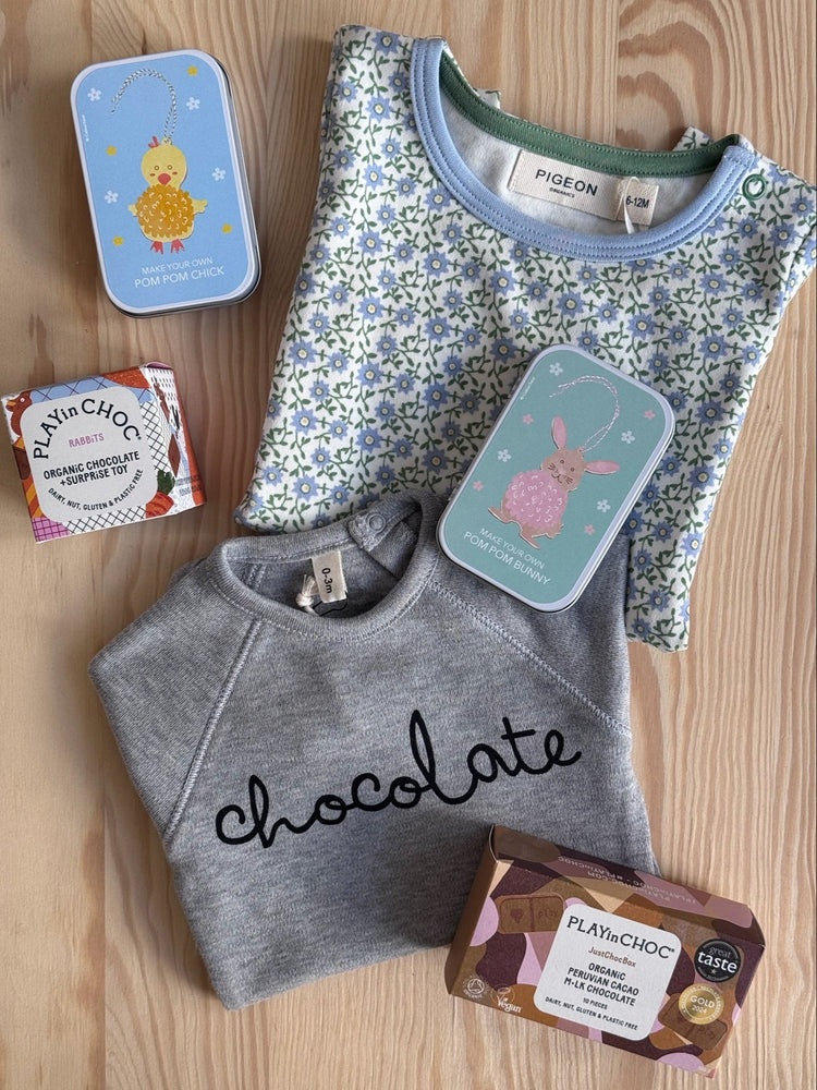 flat lay of various gifts, baby grows, craft kits and chocolates on a wooden background
