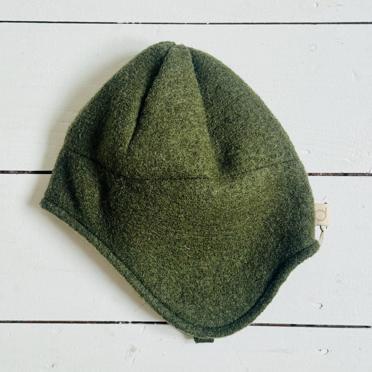 Green knitted beanie on a white wooden surface